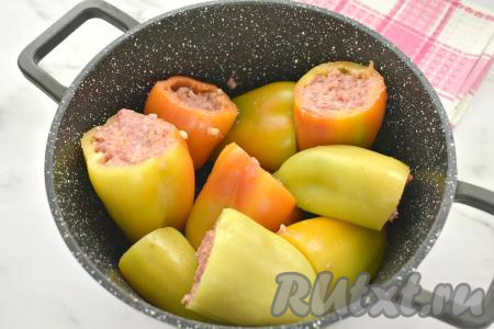 Наполняем подготовленные болгарские перцы начинкой из фарша и булгура. Фаршированные перцы выкладываем во вместительную кастрюлю.