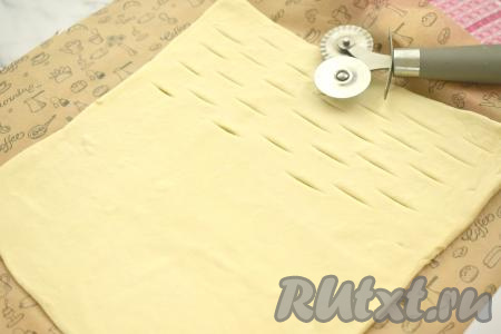 На одной половине квадрата, отступая от краёв теста по 1-1,5 сантиметра, делаем небольшие разрезы, как на фото. Я сделала разрезы ножом для нарезки пиццы и теста, можно сделать разрезы обычным ножом.