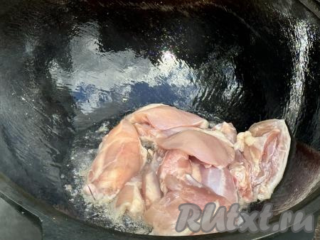 Казан поставить на костёр, влить растительное масло. Разогреть масло в течение 3-5 минут, затем выложить в казан кусочки курицы.