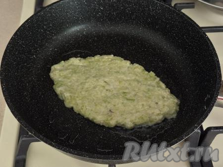 В сковороду влить растительное масло, хорошо его разогреть. Тесто разделить на 2 равные части. В сковороду, хорошо прогревшуюся с маслом, столовой ложкой выложить половину кабачкового теста, придавая ему форму хачапури в виде лодочки.