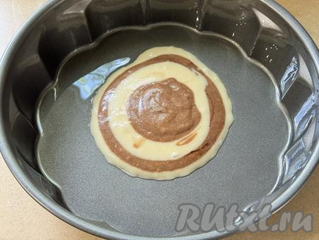 Форму для выпечки (я взяла форму диаметром 26 сантиметров) смазать растительным маслом. В середину подготовленной формы выложить 1 столовую ложку белого теста. Поверх белого теста по середине выложить 1 столовую ложку шоколадного теста. Затем поверх шоколадного теста по середине выложить 1 столовую ложку белого теста, после этого поверх белого теста по середине разместить 1 столовую ложку шоколадного теста.&nbsp;