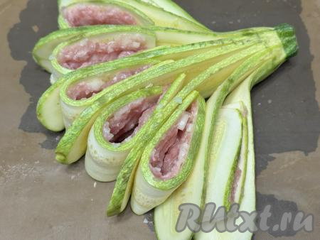 Противень застелить пергаментом (или ковриком) для выпечки, выложить остывший веер из кабачка. Полоски из кабачка, покрытые фаршем, сложить пополам и вставить между полосками вера из кабачка, как на фото. Получится красивый веер из кабачков с фаршем, внешне напоминающий цветок. Поставить противень в разогретую до 180 градусов духовку и запекать кабачок с мясом&nbsp;минут 25.&nbsp;