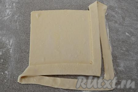 Взять один угол теста с разрезами, перекинуть его на противоположный угол, сразу прижать эту полоску к тесту, формируя бортик будущего пирога.