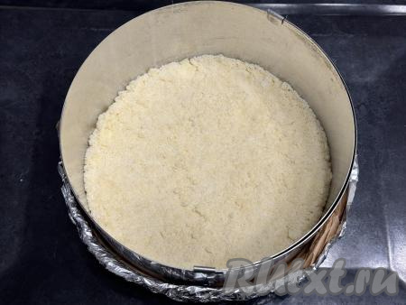 Песочную крошку разделить на 2 равные части. В разъёмную форму для выпечки диаметром 20 сантиметров выложить половину песочного теста-крошки, слегка утрамбовать. В качестве формы я взяла разъёмное кольцо диаметром 20 сантиметров, дно сформировала из пергамента и фольги, сложенной в несколько слоёв. Затем подготовленное кольцо поставила на противень и после этого выложила в получившуюся форму для выпечки половину теста-крошки.