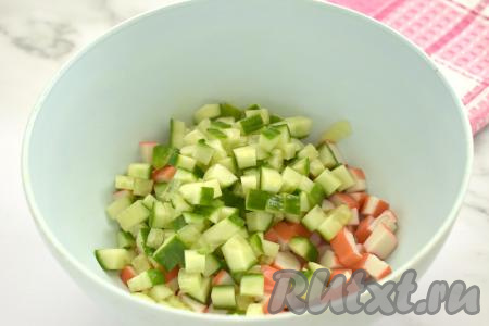 Огурец моем, обрезаем кончики с двух сторон. Нарезаем огурец на кубики примерно такого же размера, как нарезаны крабовые палочки, и тоже отправляем в миску.