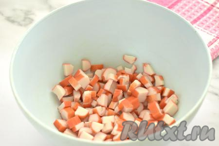 Крабовые палочки вынимаем из упаковки, нарезаем на небольшие кубики, складываем в миску.