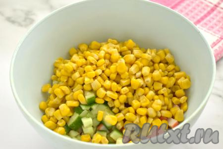 В миску с крабовыми палочками и огурцом добавляем консервированную кукурузу без жидкости.
