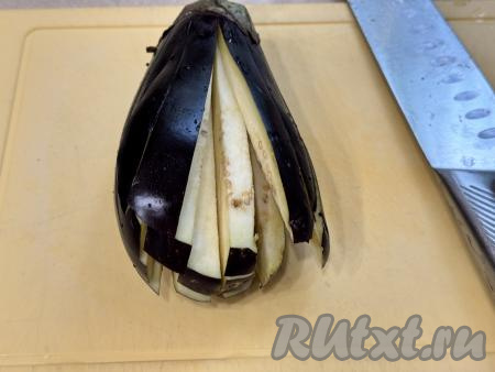 Затем повернуть баклажан и нарезать на полоски. Получатся длинные брусочки на хвостике.