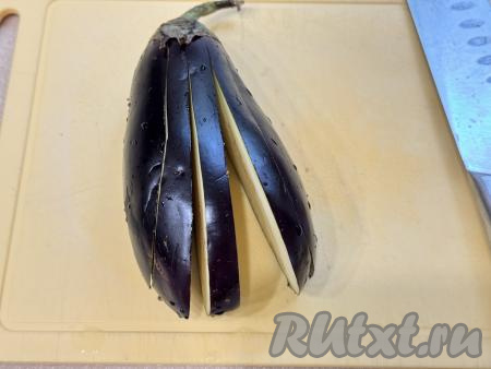 Баклажан нарезать на полоски толщиной примерно 0,5 сантиметра, не дорезая до хвостика баклажана.&nbsp;