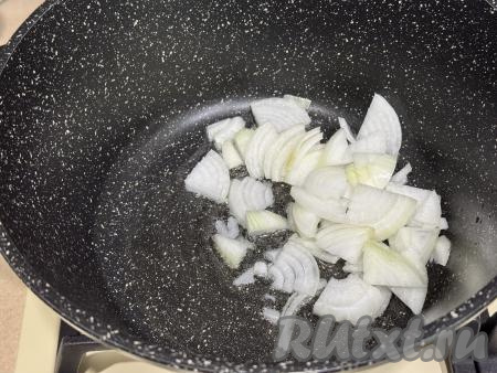 В глубокую сковороду (или в кастрюлю с толстым дном) влить растительное масло, поставить на огонь. В разогревшееся масло выложить лук, нарезанный четверть кольцами.&nbsp;
