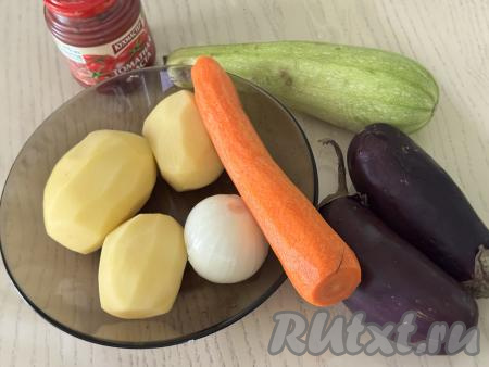 Подготовить продукты для приготовления картошки, тушёной с кабачками и баклажанами. Картошку, морковь и лук почистить. Картошку выложить в миску, залить полностью холодной водой, чтобы картофель не потемнел, пока мы будем заниматься другими овощами. Баклажаны вымыть. Кабачок я взяла с тонкой кожицей и мелкими семечками, поэтому просто обрезала у него кончики с двух сторон и промыла водой. Если у кабачка жёсткая кожура - её нужно будет срезать, крупные семечки нужно будет удалить.&nbsp;