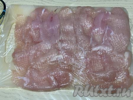 Выложить кусочки мяса на разделочную доску в один слой, накрыть филе пищевой плёнкой и слегка отбить кулинарным молоточком.&nbsp;