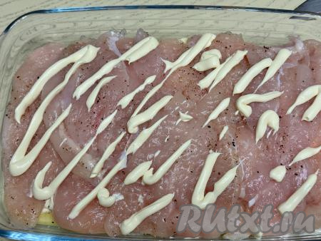 Выложить отбитые кусочки мяса курицы поверх картошки, нанести сетку из майонеза.&nbsp;