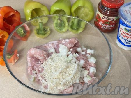 Из болгарского перца удалить семена с перегородками, аккуратно отрезав верх перцев ("хвостики" из отрезанного верха я удалять не стала). Отрезанные части перцев станут "крышечками" для фаршированных перцев. Промыть перцы водой. Рис выложить в сито, промыть водой, лишней воде дать стечь. Отваривать рис предварительно не нужно, он успеет приготовиться в процесс тушения фаршированных перцев в мультиварке. Лук очистить, мелко нарезать (или пропустить через мясорубку).&nbsp;В миску с фаршем добавить лук и промытый рис.