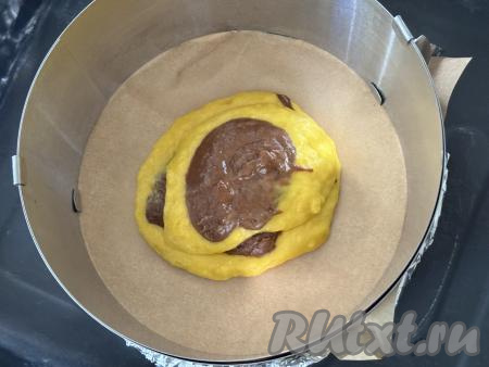 Взять разъёмную форму для выпечки диаметром 20 сантиметров, смазать её дно и бока растительным маслом. В качестве формы я взяла разъёмное кулинарное кольцо диаметром 20 сантиметров, дно формы сформировала из фольги, сложенной в несколько слоёв, и пергамента, а затем получившуюся форму поставила на противень. В подготовленную форму вначале выложить 1 столовую ложку тыквенного теста, в центр этого теста выложить 1 столовую ложку шоколадного теста, затем в центр шоколадного теста выложить 1 столовую ложку тыквенного теста.