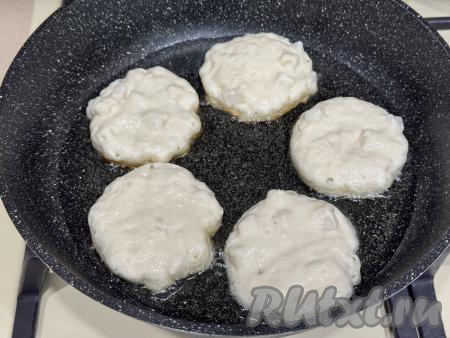 В сковороду влить растительное масло, хорошо прогреть сковороду. Выкладывать в сковороду по 1 столовой ложке теста в виде округлых оладий.