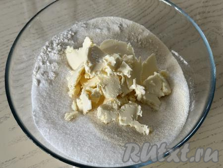 Перемешать сухие ингредиенты до однородности. Сливочное масло достать из холодильника, сразу нарезать на кусочки, выложить в миску с сухими ингредиентами.