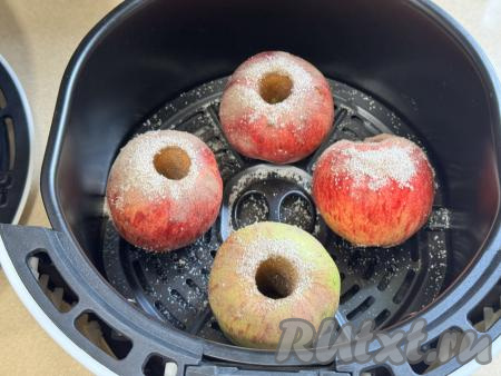 Выложить яблоки в чашу аэрогриля, присыпать сверху оставшейся смесью сахара и корицы.