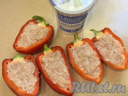 Так как перцы мы будем готовить с плодоножкой, каждый болгарский перец нужно тщательно промыть снаружи. Затем разрезать перцы на две половинки, удалить семечки и крупные перегородки, снова промыть водой. Выложить начинку из фарша и риса в половинки перца.&nbsp;