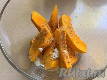 Выложить тыкву в миску, добавить&nbsp;пропущенный через пресс чеснок, соль и чёрный молотый перец, влить растительное масло. Хорошо перемешать, покрывая тыкву специями и маслом со всех сторон.