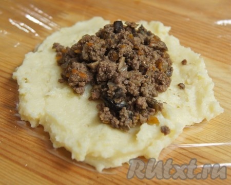 На разделочную доску стелим пищевую пленку, слегка смазываем маслом (можно присыпать мукой, но мне этот способ нравится больше). Мокрой ложкой берем картофель, кладем на смазанную пленку, придавливаем пюре, чтобы получилась лепешка. В центр зразы кладем начинку из мяса и грибов, края залепляем.