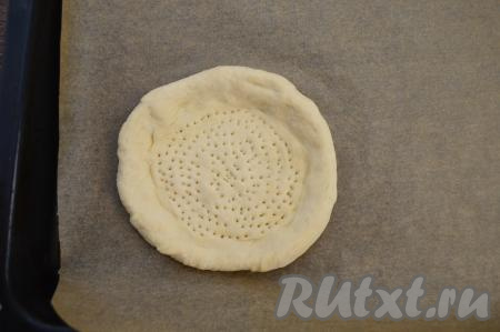 Сформированную лепёшку переложить на противень, застеленный пергаментом. При помощи вилки сделать на плоской части лепёшки глубокие наколы.