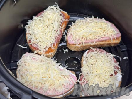 Сыр натереть на мелкой тёрке и разложить поверх бутербродов с колбасой. Установить чашу в аэрогриль.