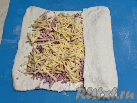 Начиная с узкого края пласта, сделать один заворот теста с начинкой на 1/3 длины (как на фото). Затем сделать ещё два заворота, сформировав плоский рулет.