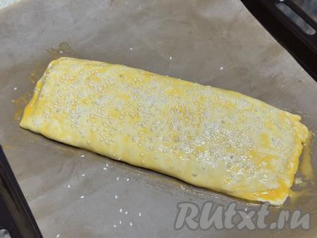 В небольшой ёмкости яичный желток взбить вилкой до однородности. Сверху всю поверхность рулета смазать взбитым желтком. По желанию присыпать рулет кунжутом.