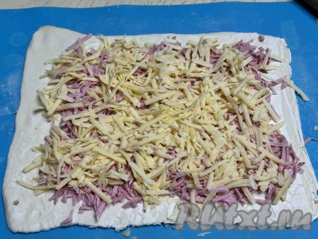 Поверх колбасы равномерно распределить сыр, натёртый на крупной тёрке.