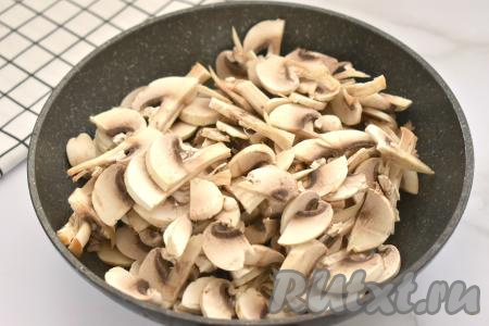 К обжаренному луку выкладываем шампиньоны, нарезанные на ломтики (или нарезанные на части отваренные лесные грибы), перемешиваем, обжариваем 7-10 минут (до испарения влаги), иногда помешивая, затем убираем с огня, даём остыть.