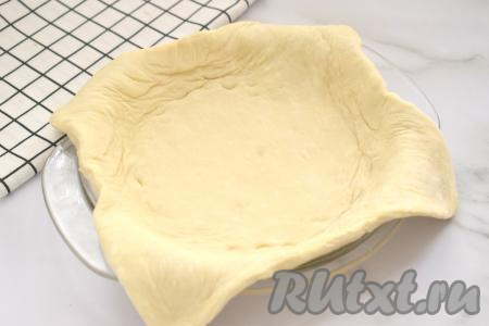 Разморозившееся слоёное тесто на слегка присыпанной мукой поверхности скалкой раскатываем в пласт толщиной 3 миллиметра. Форму для выпечки (я использовала форму диаметром 18 сантиметров) немного смазываем растительным маслом, выкладываем слоёное тесто, закрывая дно и бортики формы.