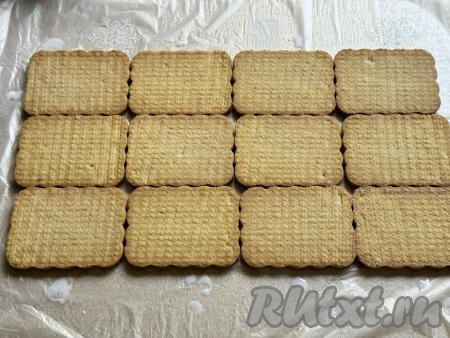 Печенье, смоченное в молоке, выложить поверх целлофана, формируя прямоугольник, как на фото, и отступая от краёв целлофана.