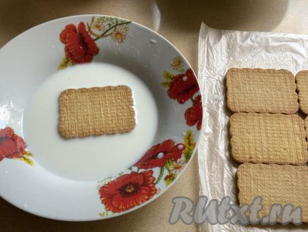 Расстелить на столе целлофановый пакет. В глубокую миску влить молоко. Обмакнуть печенье в молоко с двух сторон.