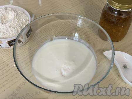 Прежде всего замесим бездрожжевое тесто на кефире для пирожков с вареньем. Кефир можно взять любой жирности (у меня - жирностью 2,5%). Желательно, чтобы кефир был комнатной температуры, для это его можно подогреть в течение 30 секунд в микроволновке, либо заранее достать из холодильника, чтобы он успел согреться. В достаточно объёмную миску влить кефир, добавить соду, перемешать и подождать 5 минут. Кефир вступит в реакцию с содой, немного увеличится в объёме, на его поверхности появятся пузырьки.