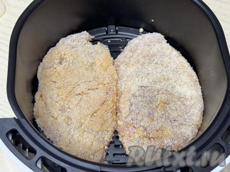 Выложить куриный шницель в панировке в чашу аэрогриля. Аналогично подготовить второй шницель в панировке, выложить его в чашу аэрогриля рядом с первым шницелем. Выставить режим 180 градусов, время - 20 минут.&nbsp;