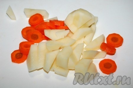 Поставить кастрюлю с водой на огонь, опустить в воду нарезанные небольшими кусочками картофель и морковь. Довести до кипения и уменьшить огонь.