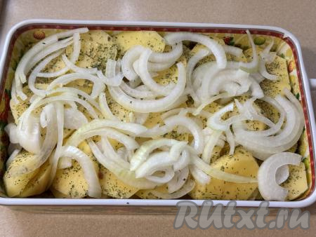 Поверх картошки разложить лук, нарезанный полукольцами.&nbsp;