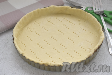 Для выпечки пирога я использовала круглую форму диаметром 22 сантиметра с бортиками высотой 2,8 сантиметра. Дно и бока формы смазываем растительным маслом.&nbsp;Размороженный пласт слоёного теста выкладываем на стол, присыпанный мукой, раскатываем в квадратный пласт со сторонами примерно 27 сантиметров. Раскатанный пласт выкладываем в круглую форму. Формируем бортики, а края теста, которые выходят за края формы, подрезаем кулинарными ножницами. Тесто, находящееся на дне формы достаточно часто накалываем вилкой, чтобы оно сильно не поднималось во время выпечки.