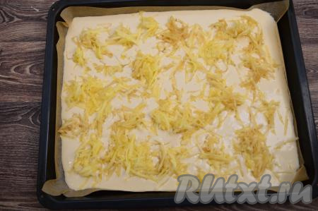 Яблоки очистить от кожуры, натереть на крупной тёрке, не затрагивая семенную коробку с косточками. Равномерно распределить натёртые яблоки по противню с блинным тестом.