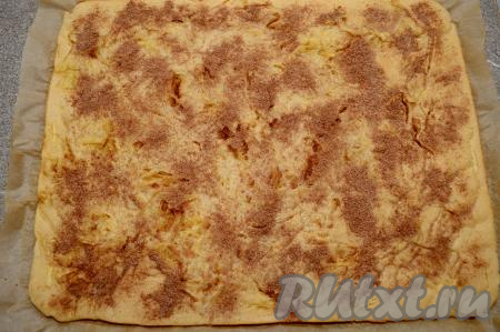 Противень с готовым блином с яблоками достать из духовки. Переложить блин вместе с пергаментом с противня на стол. Присыпать блин смесью корицы и сахара.