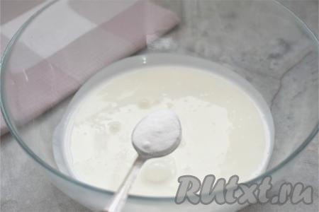 Пока остывает начинка, приступаем к замешиванию теста. Кефир можно использовать любой жирности (я купила жирностью 2,5%). Подогреваем кефир до комнатной температуры (я подогрела в течение 30 секунд в микроволновке), можно просто заранее достать кефир из холодильника, чтобы он успел согреться. В глубокую миску выливаем кефир, всыпаем соду, очень хорошо перемешиваем столовой ложкой (или венчиком) и оставляем минут на 5. В течение этого времени сода погасится в кислой среде кефира, поэтому кефир немного увеличится в объёме, на его поверхности появятся пузырьки.