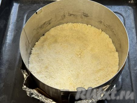 Разделить получившуюся песочную крошку на 3 равных части. Взять разъёмную форму для выпечки диаметром 20 сантиметров. Я в качестве формы использовала разъёмное кольцо диаметром 20 сантиметров, дно сформировала из пергамента и фольги, сложенной в несколько слоёв, затем поставила получившуюся форму на противень. В форму для выпечки выложить 1/3 часть крошки, слегка утрамбовать.