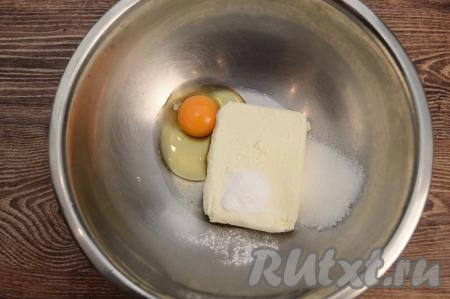 По прошествии 5 минут слить воду с изюма, разложить его на бумажном полотенце, чтобы избавиться от воды. Осмотреть изюм, удаляя, если они есть, мелкие веточки. Пока изюм обсыхает, нужно в глубокую миску выложить творог, вбить яйцо, всыпать сахар и разрыхлитель.&nbsp;