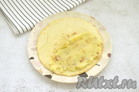 Готовую лепёшку перекладываем со сковороды на тарелку. На одну половину горячей лепёшки выкладываем 2 столовых ложек начинки из картошки, разравниваем.
