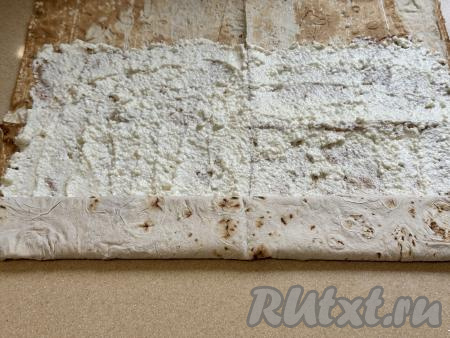 Свернуть лаваш с творогом в плоский рулет, начиная с более узкой стороны.&nbsp;