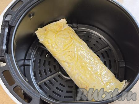 Яичный желток в небольшой ёмкости взбить вилкой до однородности. Вначале одну часть рулета с творогом выложить в чашу аэрогриля, смазать поверхность лаваша взбитым желтком.