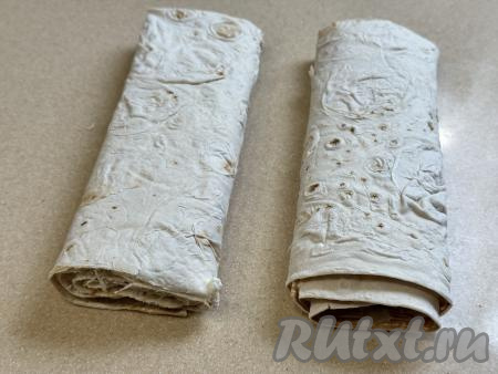 Сформированный рулет с творогом разрезать на 2 части. Рулет из лаваша целиком не поместится в чашу аэрогриля, поэтому его нужно разрезать на 2 части.