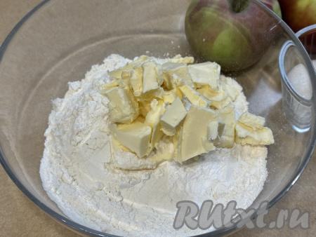 Сливочное масло достать из холодильника, нарезать на небольшие кусочки, добавить в миску с сухими ингредиентами.