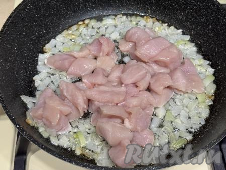 Обжарить лук на среднем огне до прозрачности (в течение 3-4 минут), иногда помешивая. После того как лук станет прозрачным, добавить к нему куриное мясо, нарезанное на средние кусочки, перемешать.&nbsp;
